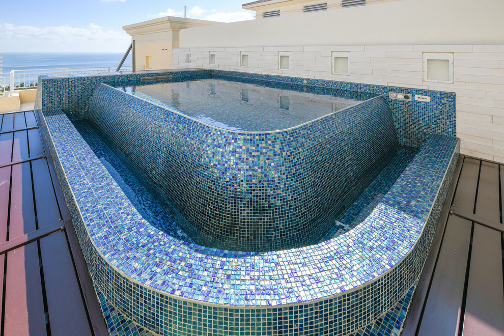 Photo of a small mediterranean roof custom shaped infinity hot tub in Other with natural stone paving.