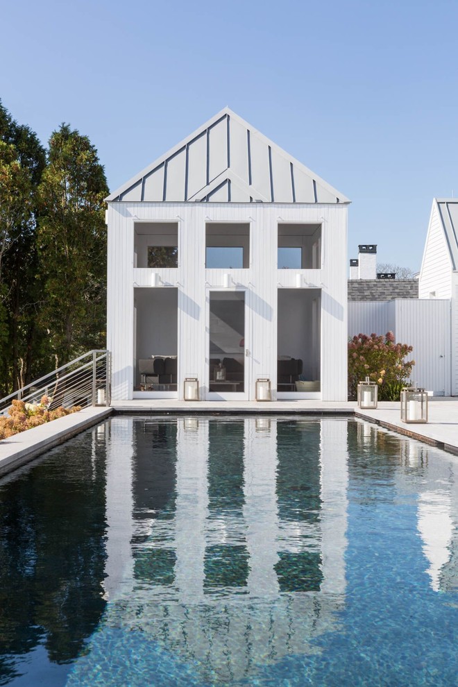 Ejemplo de casa de la piscina y piscina alargada moderna grande rectangular en patio trasero con losas de hormigón