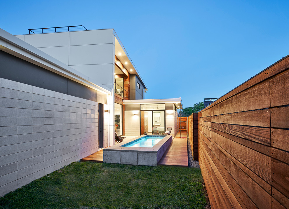 Modelo de piscina alargada moderna de tamaño medio rectangular en patio lateral con entablado