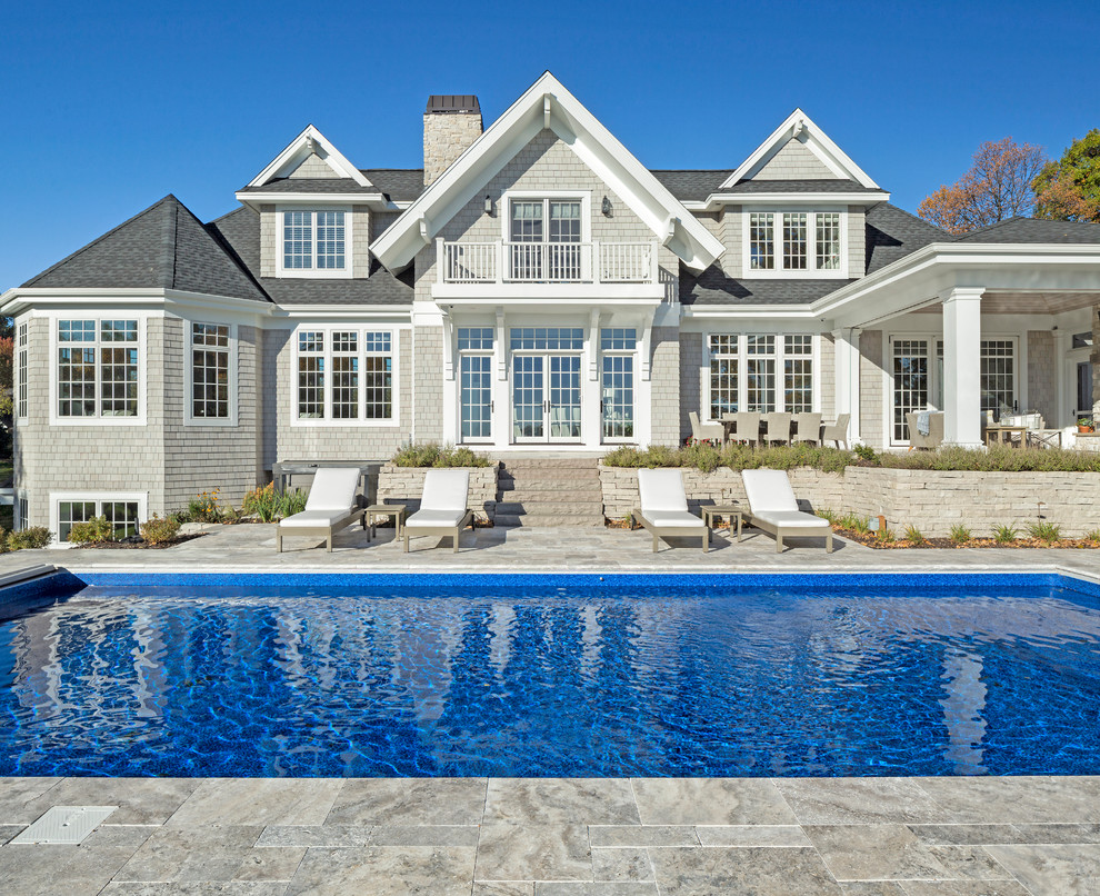 Immagine di una piscina stile marino rettangolare dietro casa con pavimentazioni in pietra naturale