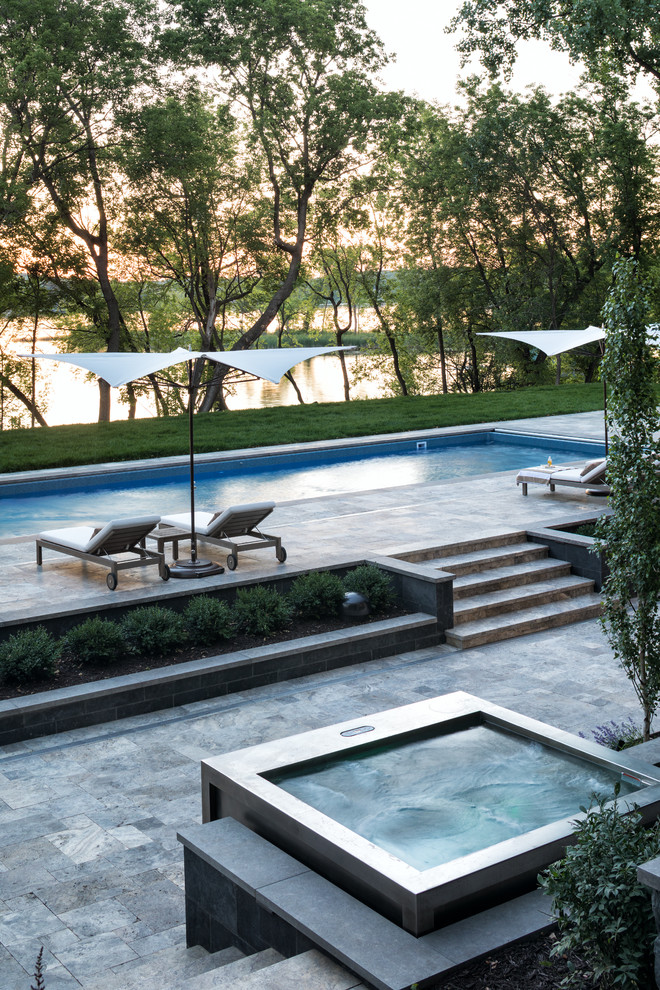 Modelo de piscinas y jacuzzis tradicionales renovados en patio trasero con adoquines de piedra natural