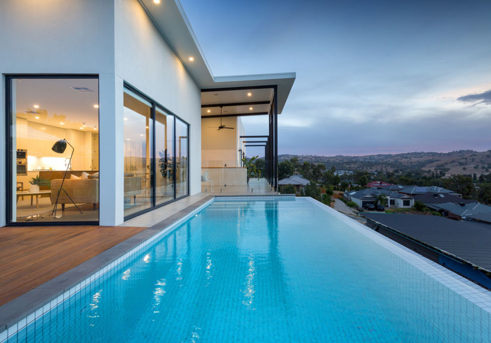 Aménagement d'une grande piscine sur toit à débordement contemporaine rectangle avec une terrasse en bois.