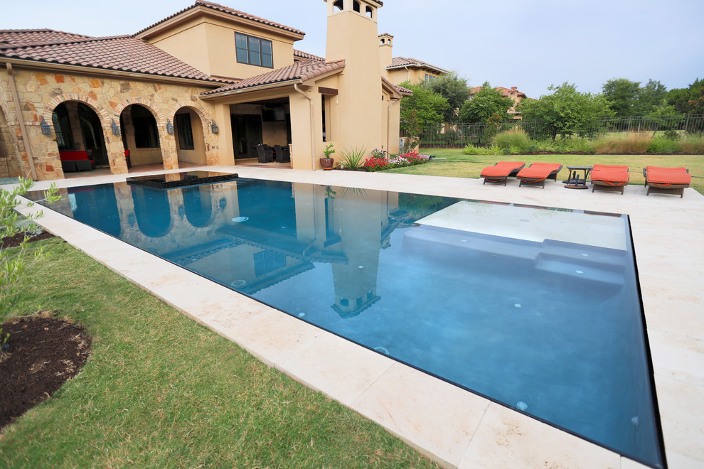Пример оригинального дизайна: большой прямоугольный бассейн-инфинити на заднем дворе в средиземноморском стиле с джакузи и покрытием из каменной брусчатки