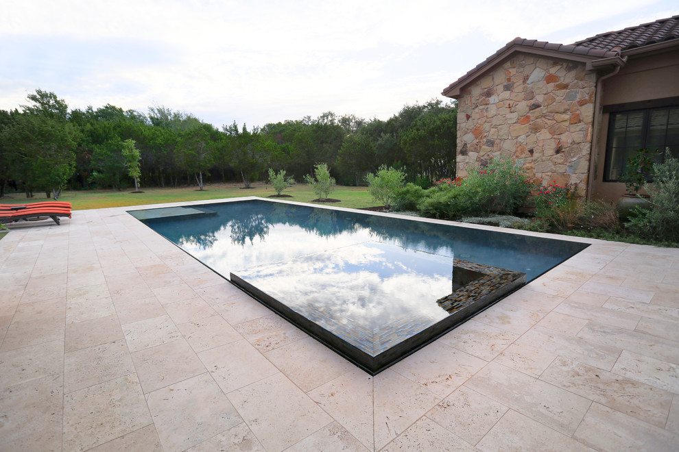Esempio di una grande piscina a sfioro infinito mediterranea rettangolare dietro casa con una vasca idromassaggio e pavimentazioni in pietra naturale