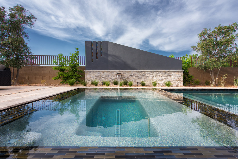 Immagine di una piscina a sfioro infinito moderna rettangolare di medie dimensioni e dietro casa con pavimentazioni in pietra naturale