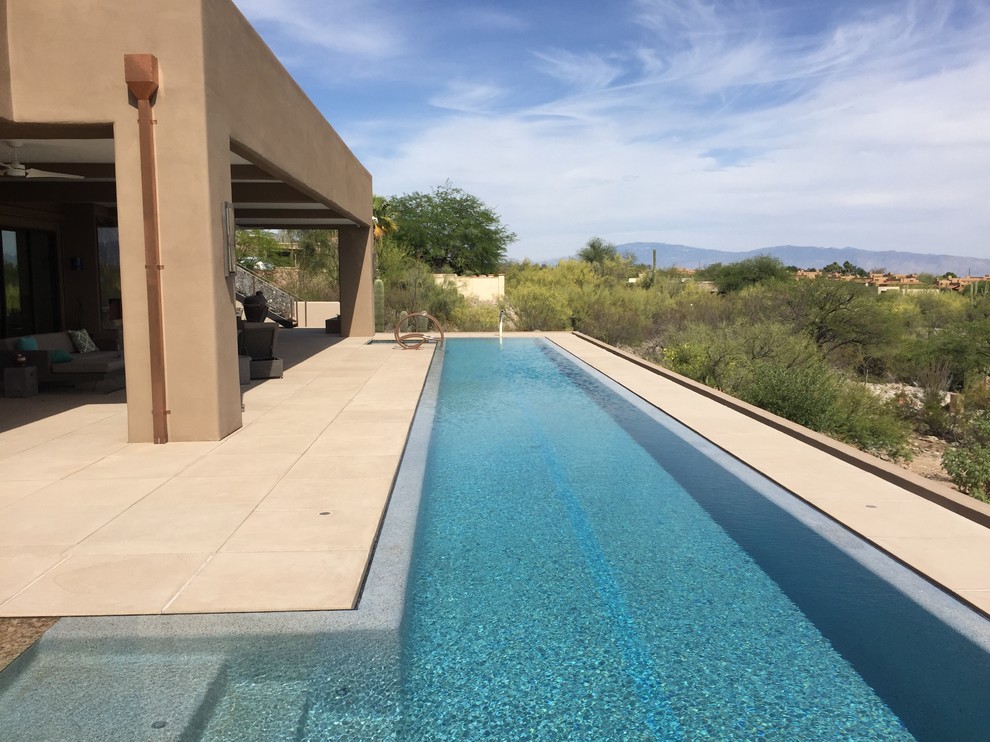 Foto di un'ampia piscina a sfioro infinito minimal personalizzata dietro casa con pavimentazioni in cemento