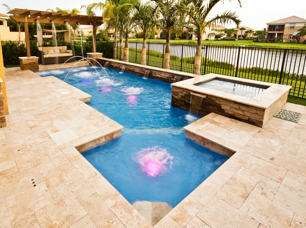 Ejemplo de piscina con fuente alargada mediterránea grande a medida en patio trasero con adoquines de piedra natural