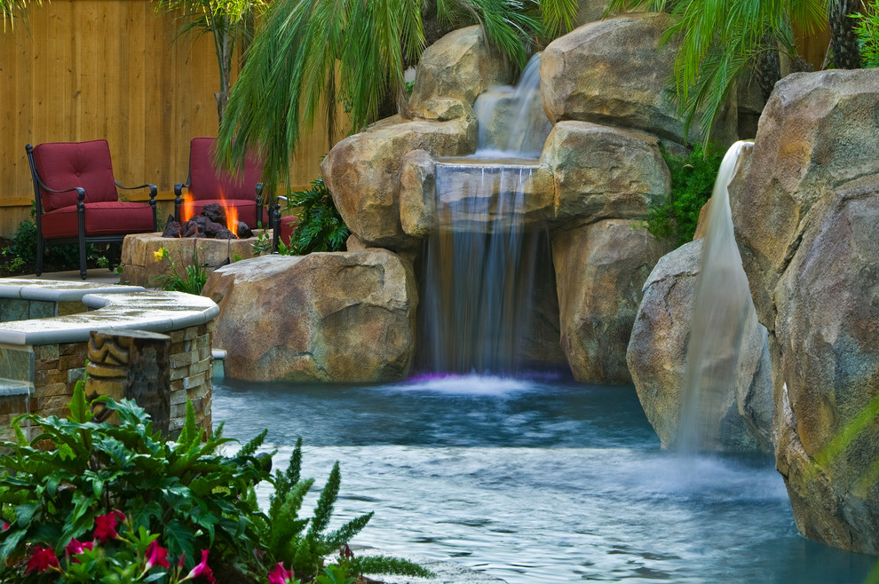Exemple d'une piscine arrière exotique de taille moyenne et sur mesure avec un bain bouillonnant et des pavés en pierre naturelle.