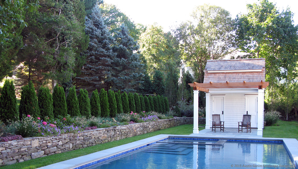 Inredning av en lantlig liten rektangulär pool längs med huset, med poolhus och naturstensplattor