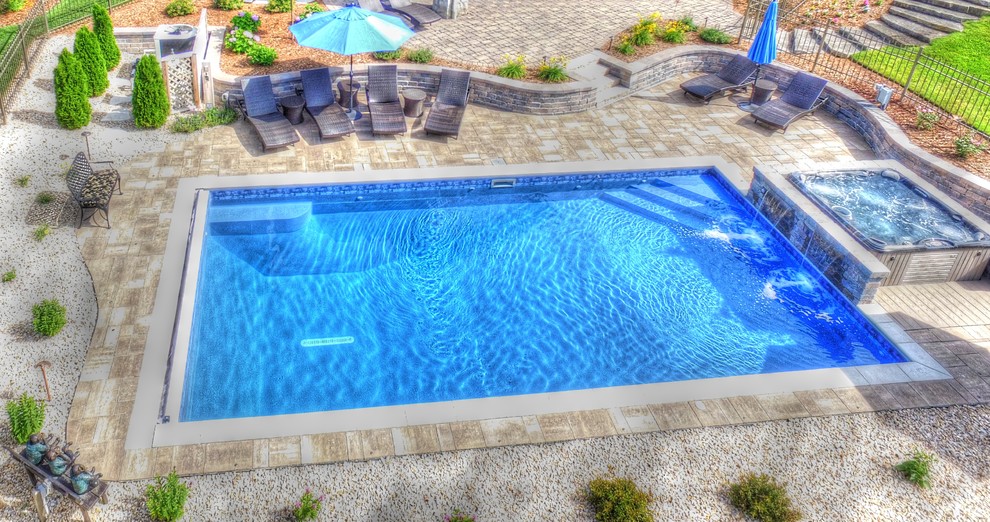 Idée de décoration pour une petite piscine arrière craftsman rectangle avec un bain bouillonnant et des pavés en béton.