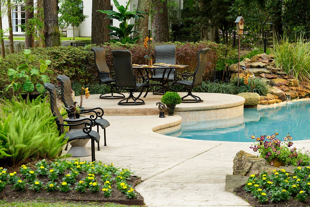 Inspiration for a classic back custom shaped natural swimming pool in Houston with a water feature and stamped concrete.