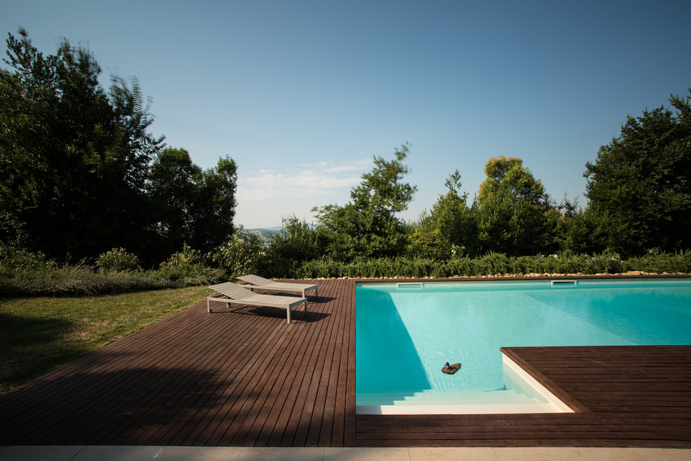 Immagine di una grande piscina mediterranea a "L" davanti casa con una dépendance a bordo piscina e pedane
