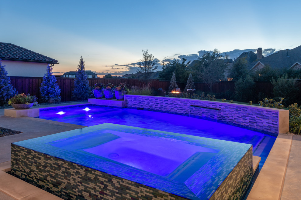 Photo of a large classic back custom shaped swimming pool in Dallas with concrete slabs.