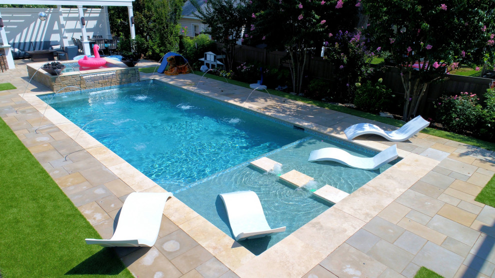 This is an example of a medium sized contemporary back rectangular swimming pool in Other with a water feature and natural stone paving.