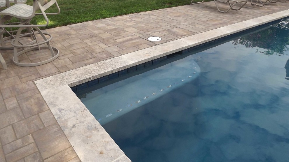 Inspiration pour une grande piscine arrière traditionnelle rectangle avec des pavés en pierre naturelle.