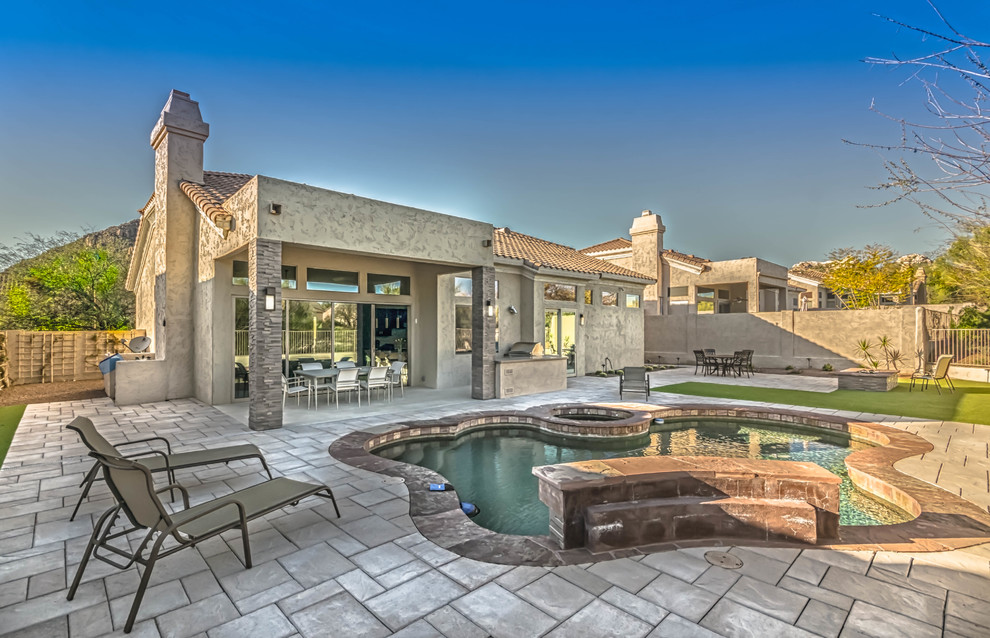 Example of a large transitional backyard stone and custom-shaped pool fountain design in Phoenix
