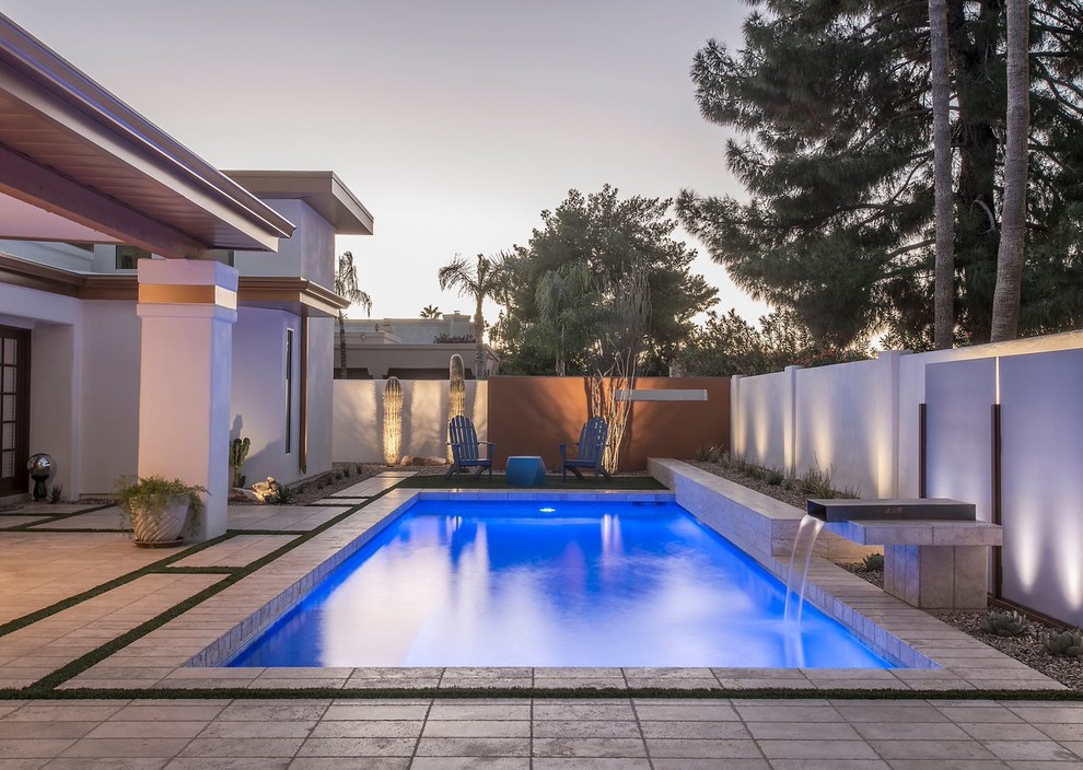 This is an example of a large contemporary back rectangular lengths swimming pool in Phoenix with a water feature and tiled flooring.