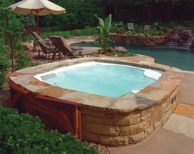 Ispirazione per una piscina classica personalizzata dietro casa con una vasca idromassaggio e pavimentazioni in pietra naturale