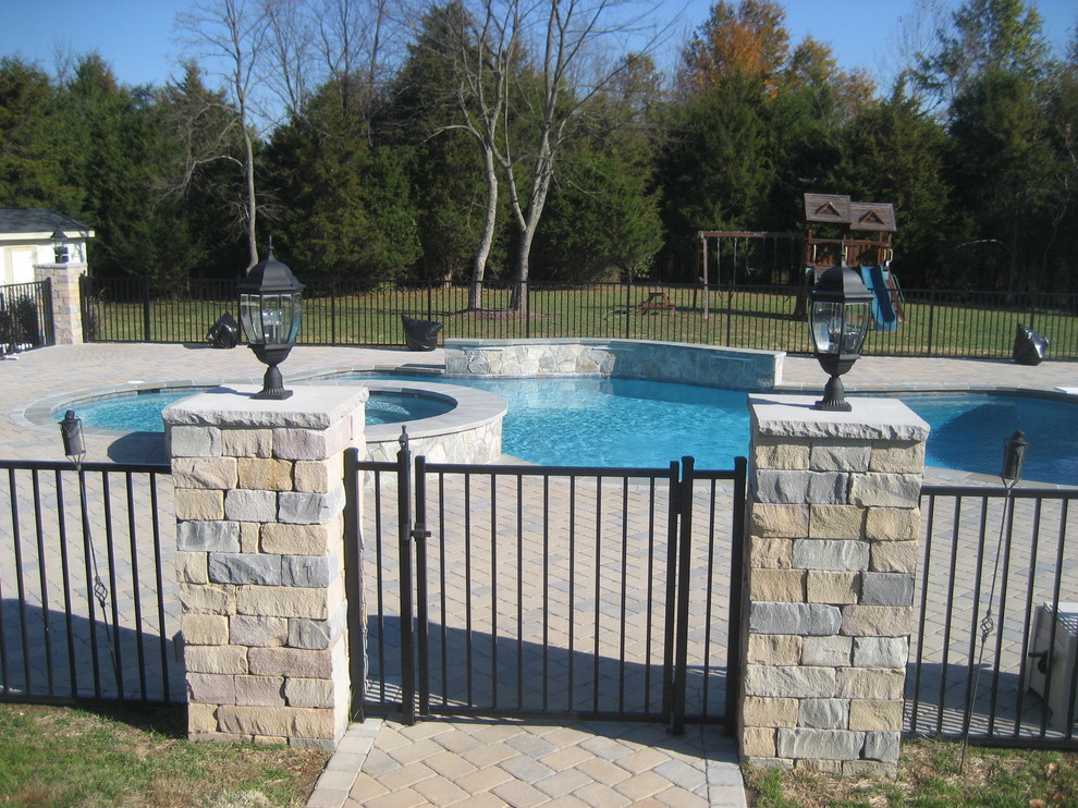 Esempio di una piscina chic personalizzata di medie dimensioni e dietro casa con una vasca idromassaggio e pavimentazioni in mattoni