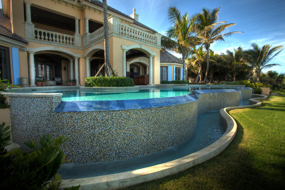 Esempio di una grande piscina monocorsia mediterranea personalizzata dietro casa con fontane e piastrelle