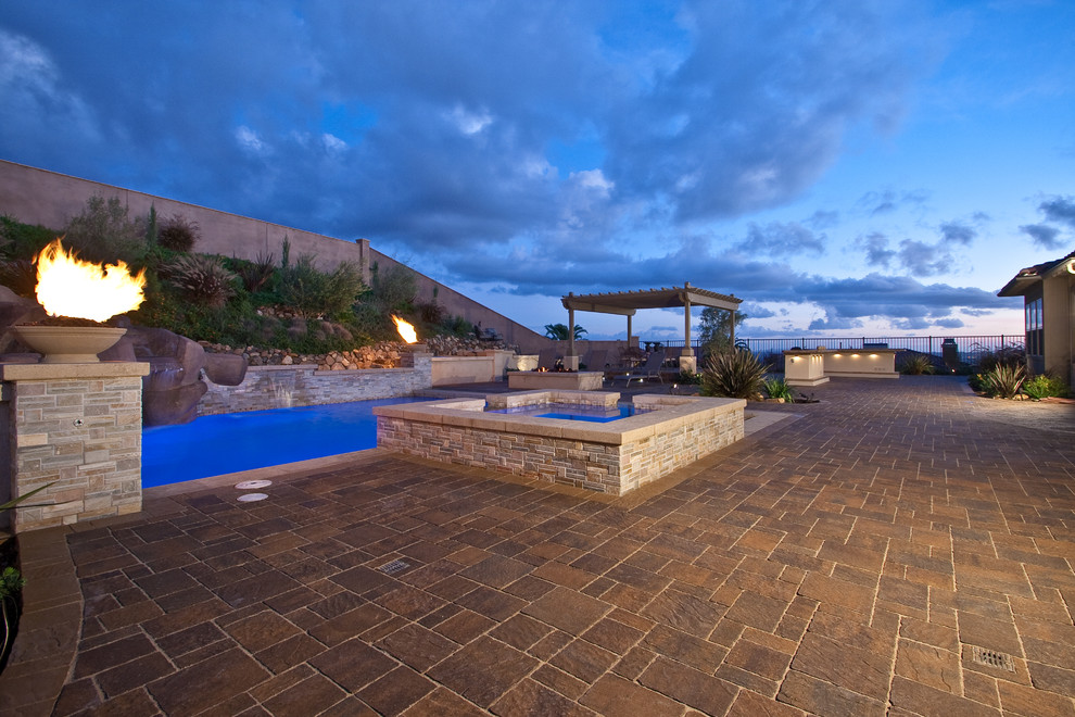 Immagine di una grande piscina naturale personalizzata dietro casa con una vasca idromassaggio e pavimentazioni in cemento