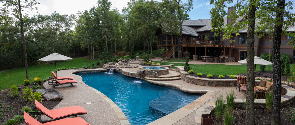 Diseño de piscina con fuente de estilo americano grande a medida en patio trasero con losas de hormigón