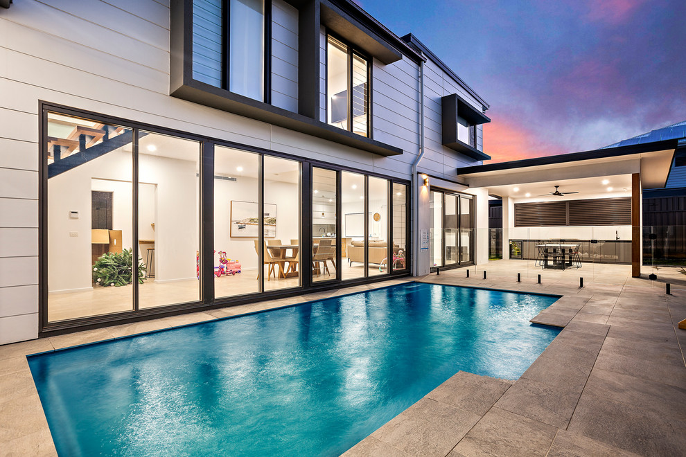 Großer Moderner Schwimmteich hinter dem Haus in rechteckiger Form mit Natursteinplatten in Wollongong