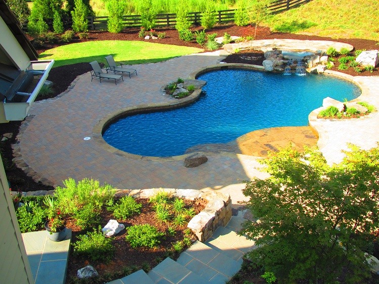 Esempio di un'ampia piscina classica personalizzata dietro casa con una vasca idromassaggio e pavimentazioni in pietra naturale