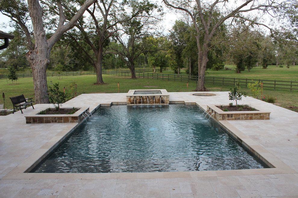 Cette photo montre un grand couloir de nage arrière chic rectangle avec un bain bouillonnant et des pavés en pierre naturelle.