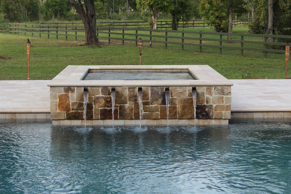Esempio di una grande piscina monocorsia tradizionale rettangolare dietro casa con una vasca idromassaggio e pavimentazioni in pietra naturale