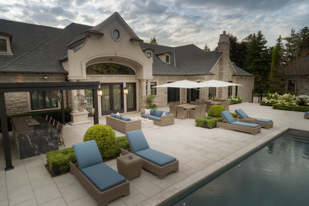 This is an example of a medium sized contemporary back rectangular lengths swimming pool in Toronto with a water feature and natural stone paving.