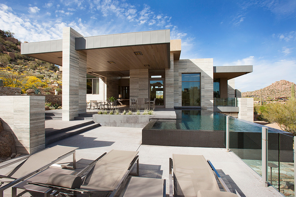 На фото: огромный прямоугольный бассейн-инфинити на заднем дворе в стиле модернизм с покрытием из бетонных плит