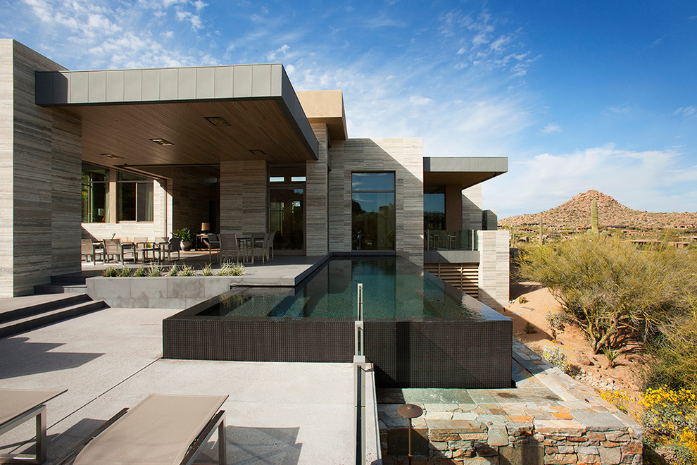 Стильный дизайн: огромный прямоугольный бассейн-инфинити на заднем дворе в стиле модернизм с покрытием из бетонных плит - последний тренд