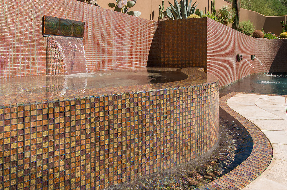 Large contemporary back custom shaped infinity swimming pool in Phoenix with a water feature and tiled flooring.