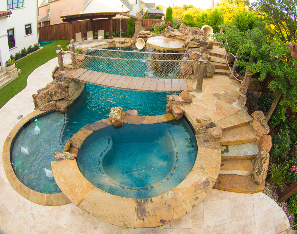 Diseño de piscina con tobogán exótica grande a medida en patio trasero con adoquines de piedra natural