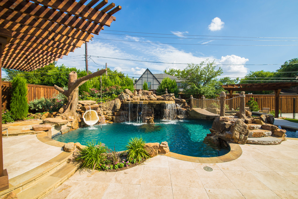 Foto de piscina con fuente natural tropical grande a medida en patio trasero con adoquines de piedra natural