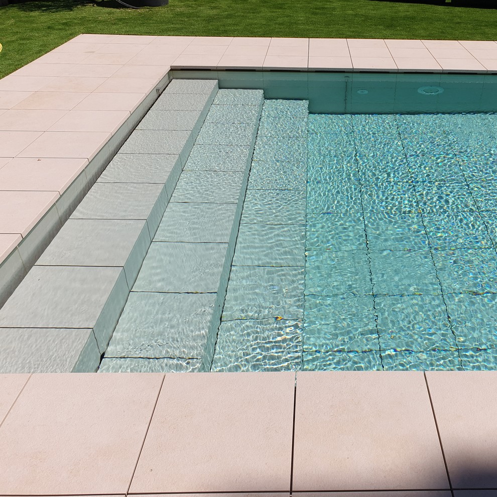 Ejemplo de piscina alargada moderna de tamaño medio a medida con suelo de baldosas
