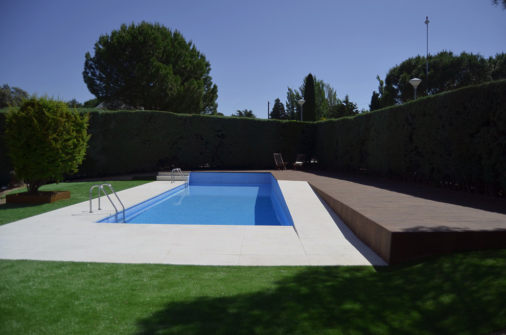 Imagen de casa de la piscina y piscina alargada moderna grande rectangular en patio delantero con suelo de baldosas