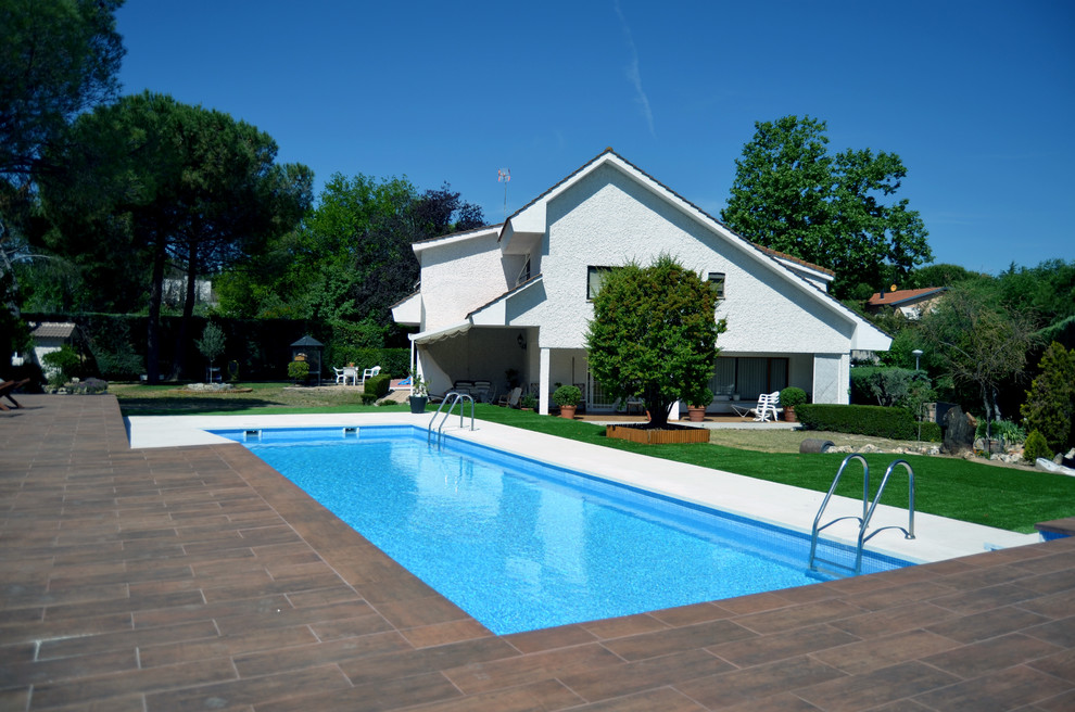 Design ideas for a large modern front rectangular lengths swimming pool in Other with a pool house and tiled flooring.