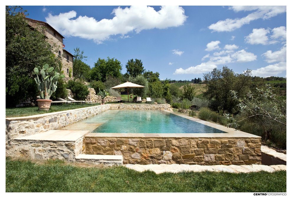 Imagen de piscina infinita tradicional de tamaño medio rectangular en patio delantero con adoquines de piedra natural