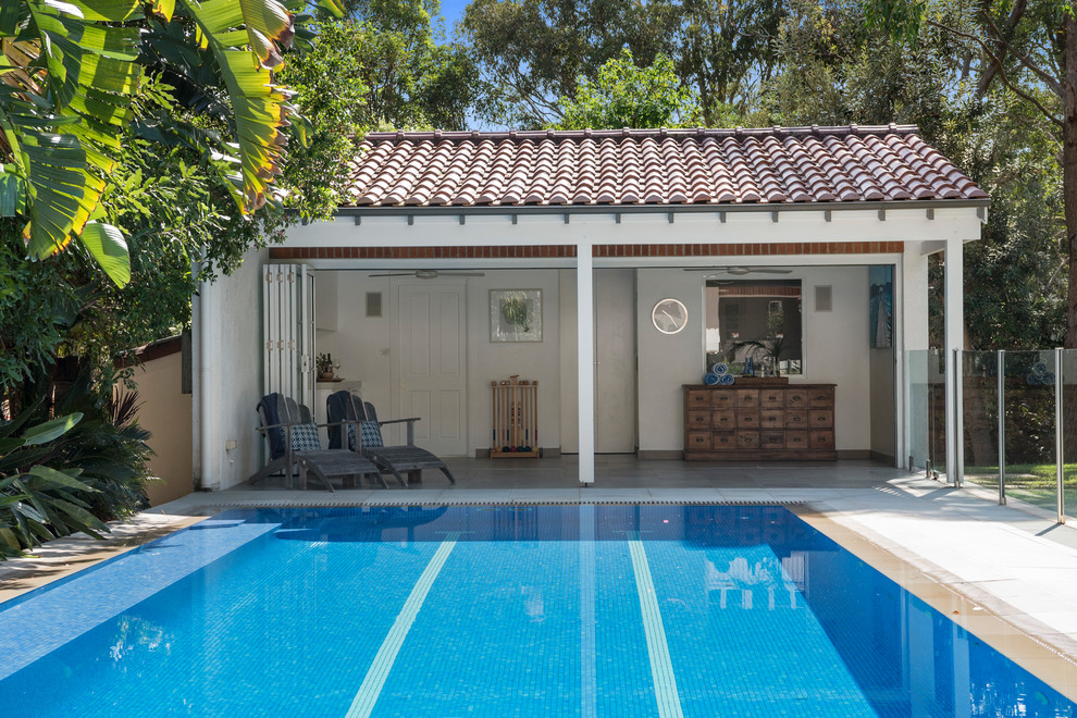 Immagine di un'ampia piscina a sfioro infinito tradizionale rettangolare dietro casa con una dépendance a bordo piscina e pavimentazioni in pietra naturale
