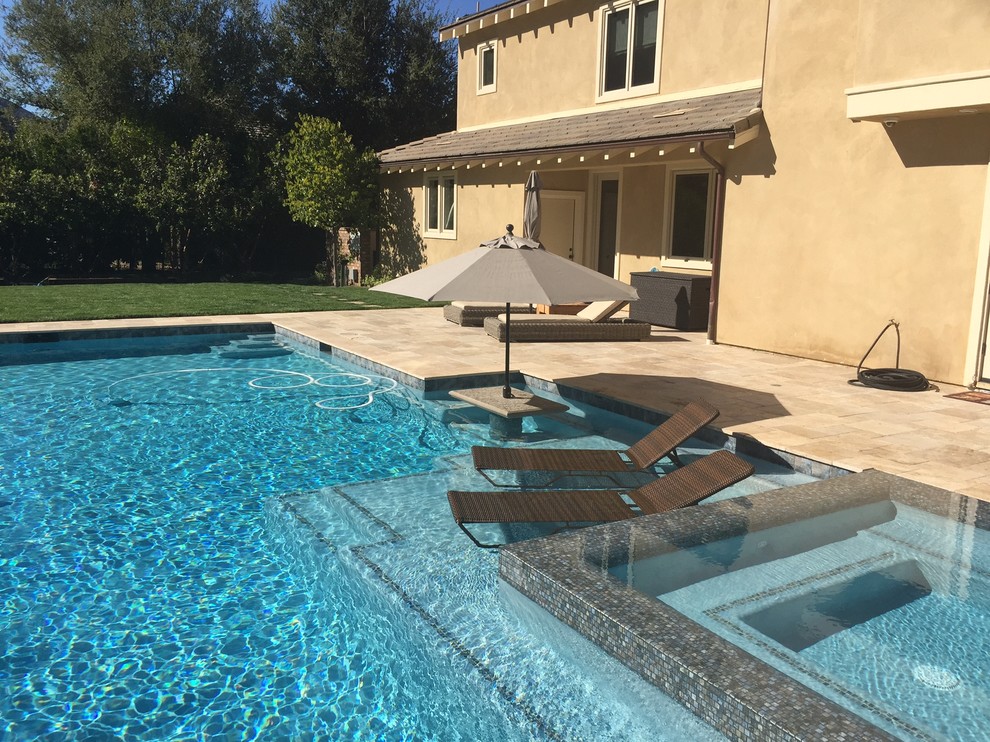 Immagine di una grande piscina a sfioro infinito tradizionale rettangolare dietro casa con una vasca idromassaggio e pavimentazioni in pietra naturale