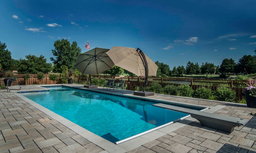This is an example of a medium sized traditional back l-shaped lengths swimming pool in Chicago with concrete paving.