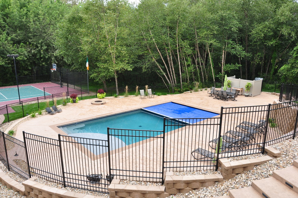 Pool - large traditional backyard stamped concrete and rectangular pool idea in Cedar Rapids