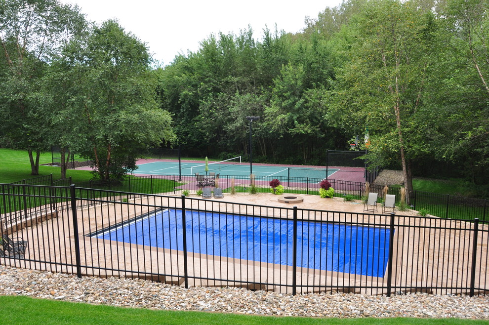 Ejemplo de piscina clásica grande rectangular en patio trasero con suelo de hormigón estampado