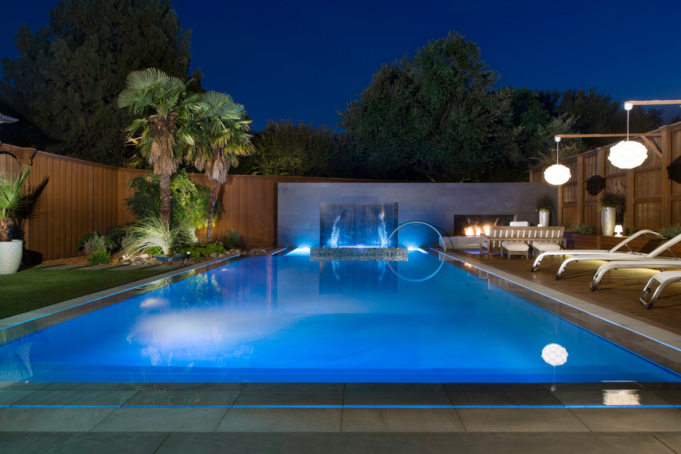 This is an example of a medium sized modern back rectangular swimming pool in Dallas with natural stone paving.
