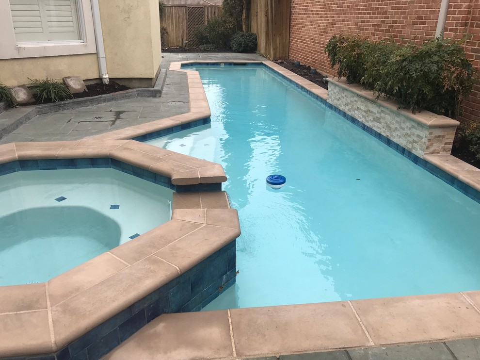 Imagen de piscina con fuente alargada actual de tamaño medio rectangular en patio trasero con suelo de baldosas