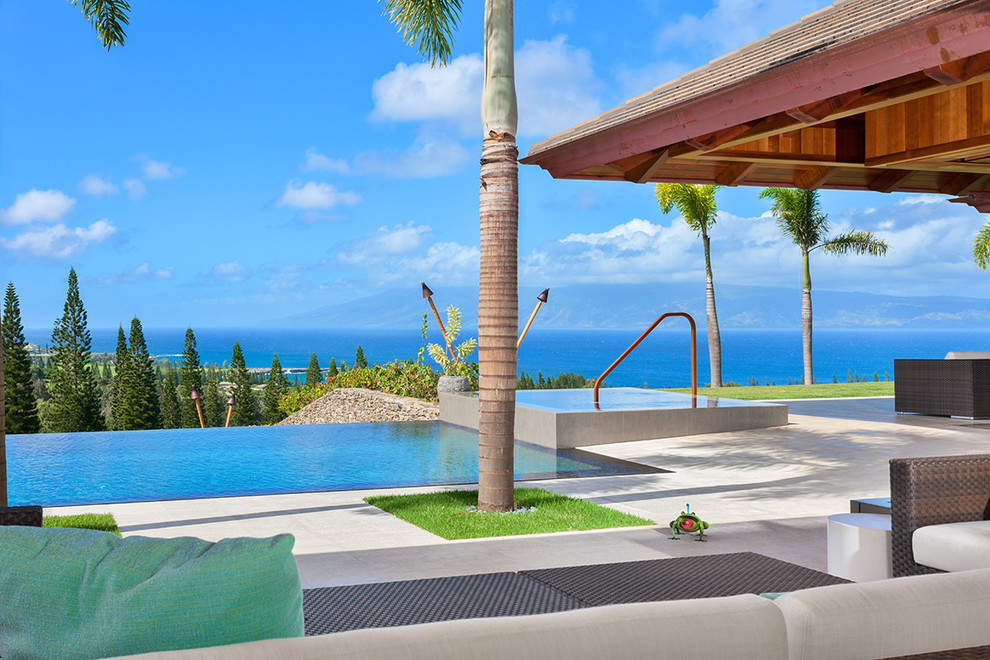 Modelo de piscinas y jacuzzis infinitos tropicales grandes rectangulares en patio trasero con losas de hormigón