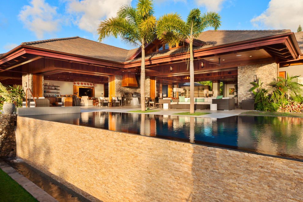 Hot tub - large tropical backyard concrete and rectangular infinity hot tub idea in Hawaii