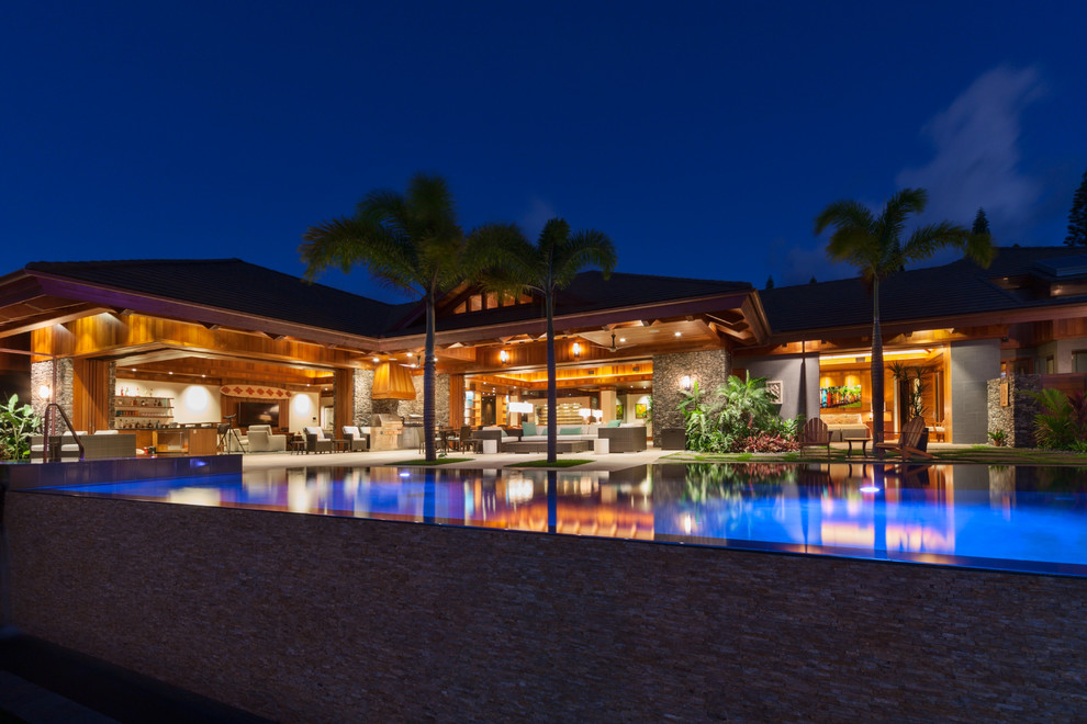 Foto de piscinas y jacuzzis infinitos tropicales grandes rectangulares en patio trasero con losas de hormigón